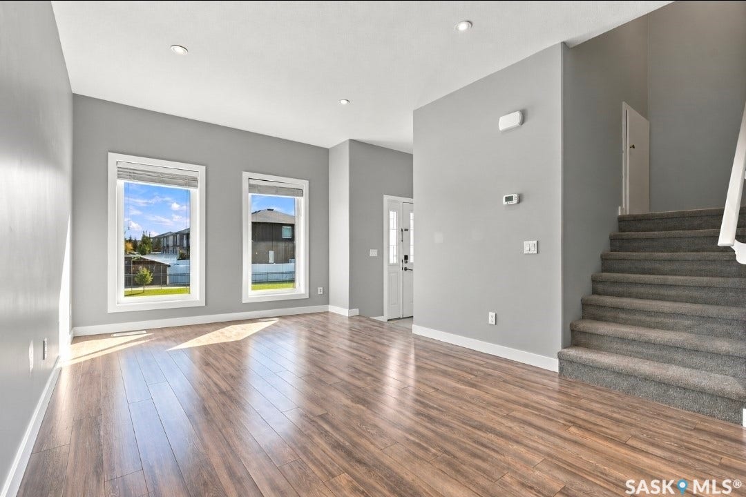 Wood-finish flooring, recessed lighting, dual windows, carpeted staircase, and neutral wall tones