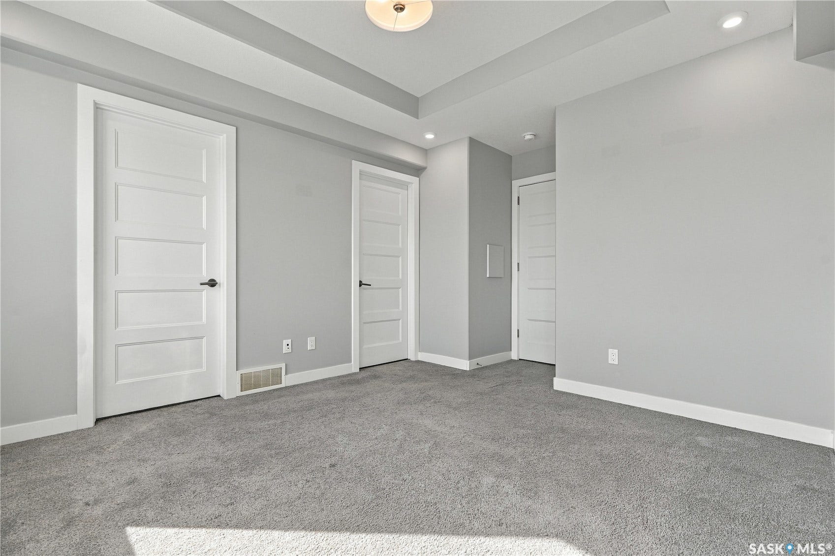 Recessed lighting, flush mount ceiling fixture, light gray walls, white trim, and gray carpeting