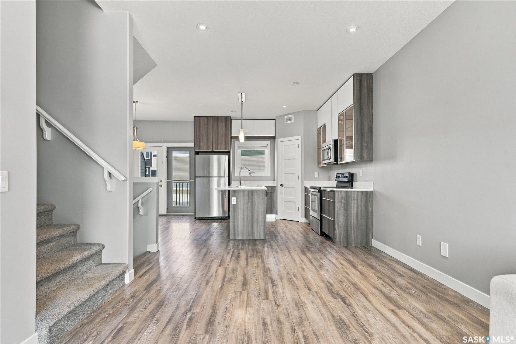 Open-concept living area featuring wood-finish flooring, recessed lighting, and a modern kitchen with stainless steel appliances