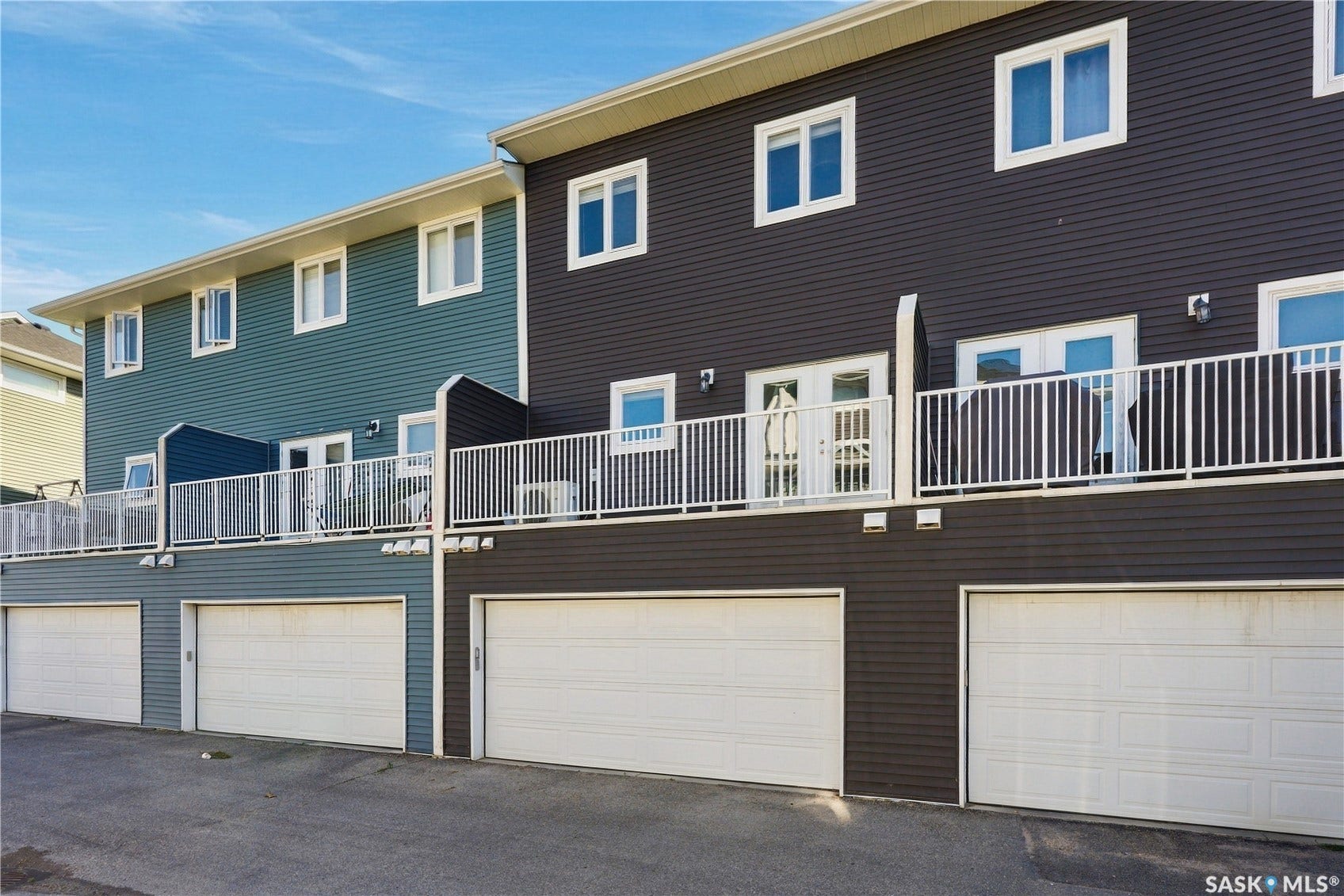 Multi-level exterior with horizontal siding, individual garage doors, multiple upper-level balconies with white railings, and white-framed windows