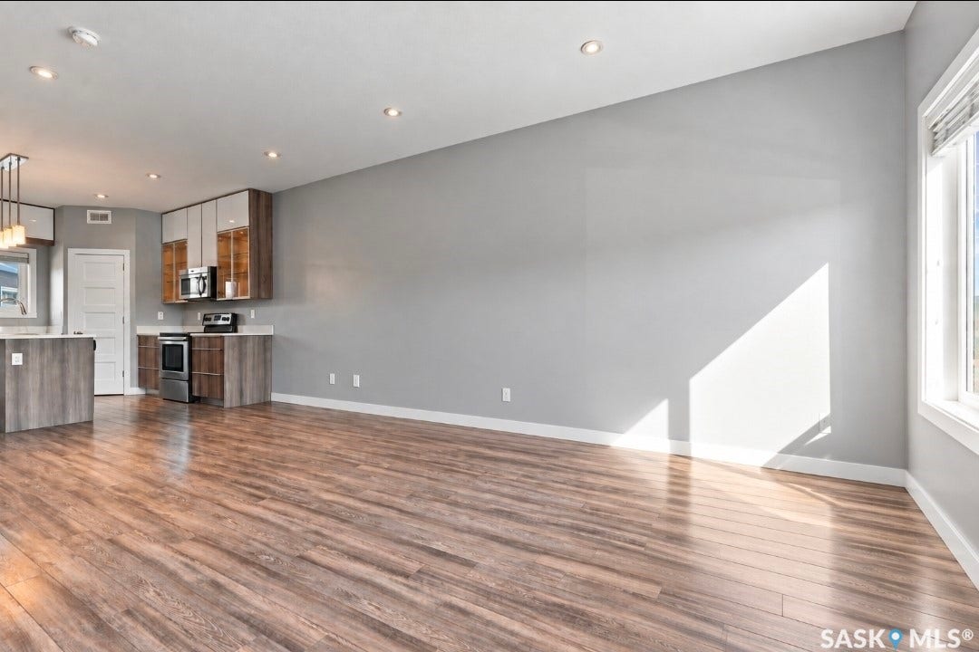 Open-concept living space featuring wood-finish flooring, recessed lighting, and a kitchen with stainless steel appliances, a kitchen island, and contemporary cabinetry