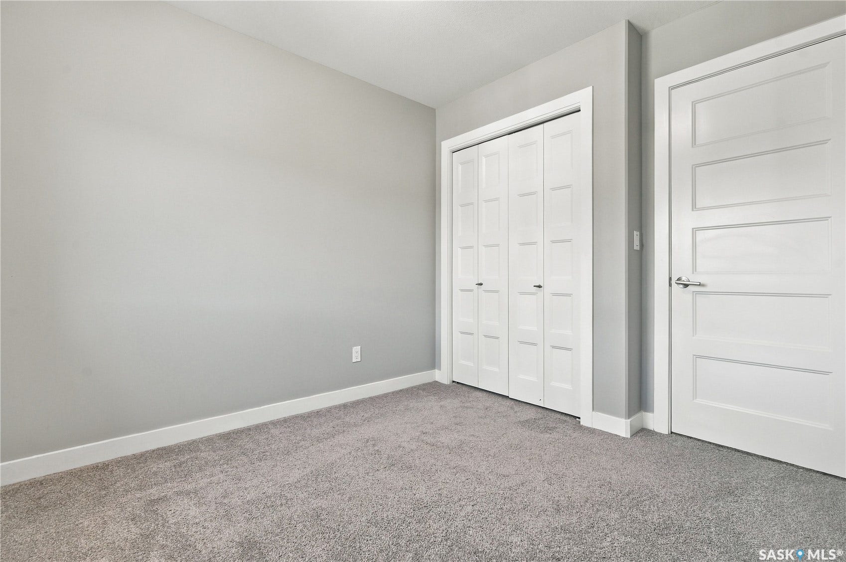 Spacious bedroom featuring neutral wall finishes, plush carpeting, and dual closets with white six-panel doors