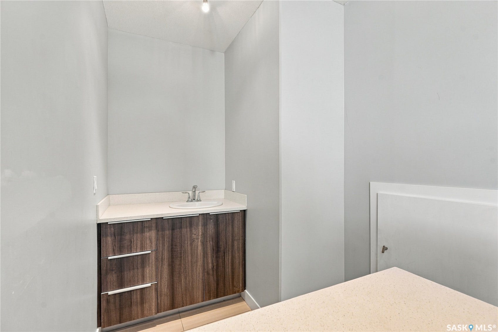 Wood-finish vanity with an integrated sink, polished chrome faucet, and light-toned countertop