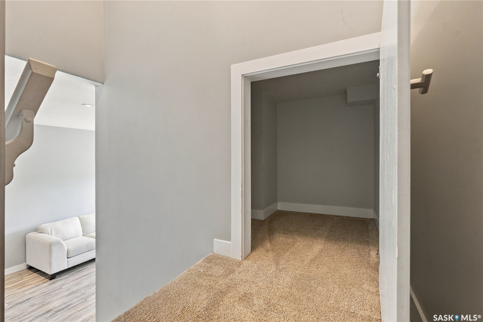 Carpeted landing leading to an open doorway, featuring light gray walls and white trim