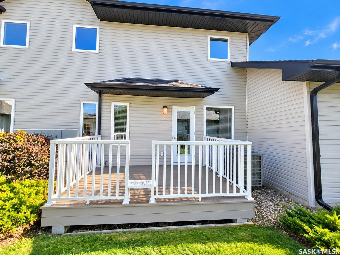Private rear deck with white railing, light gray siding, and multiple windows