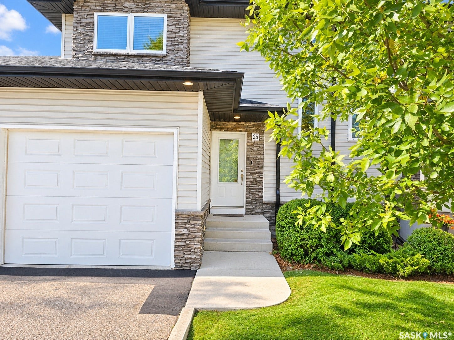 Multilevel exterior featuring siding and stone accents, an attached garage, a glass-paneled entry door, and concrete steps