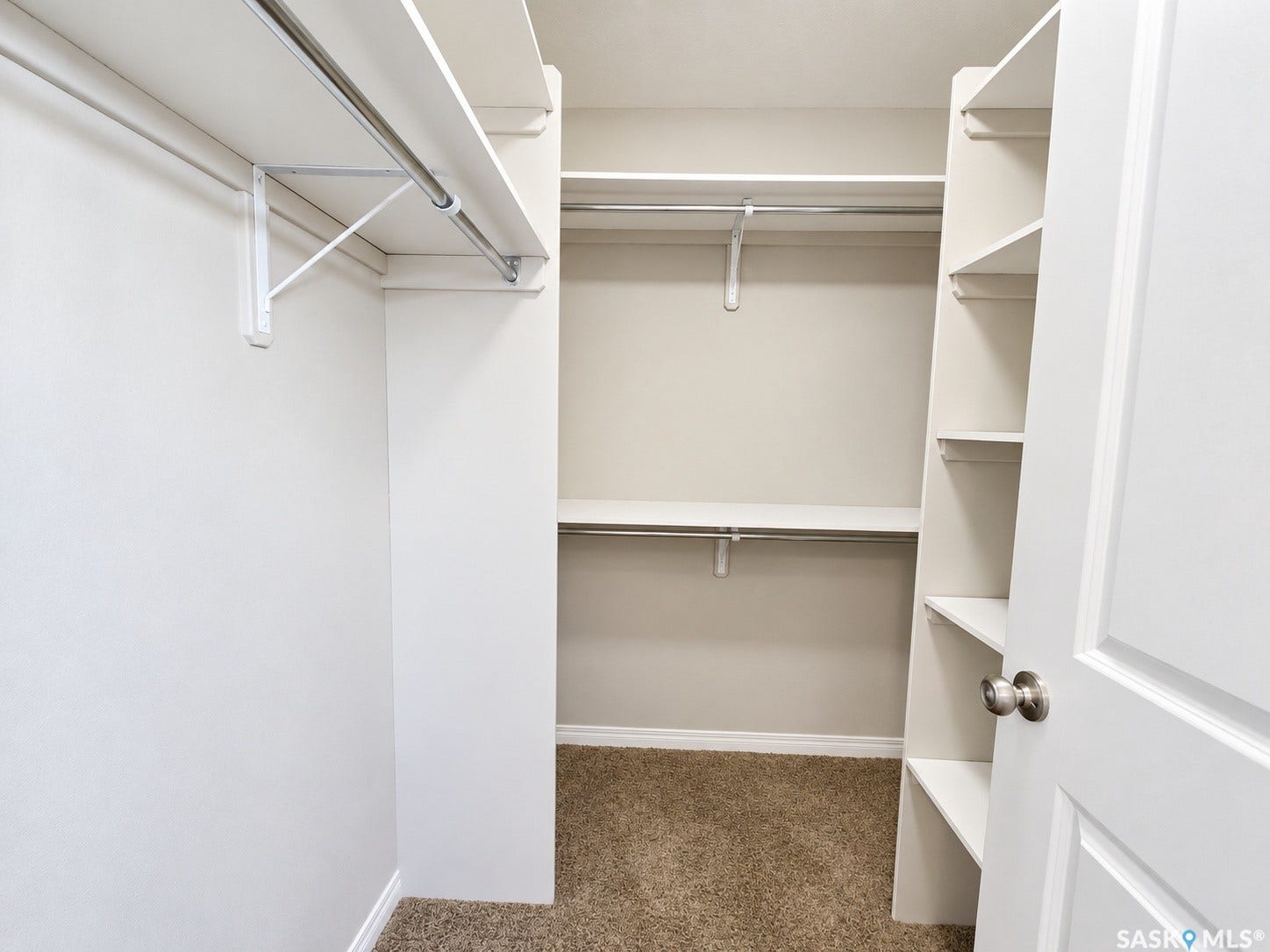 Walk-in closet featuring built-in shelving, multiple hanging rods, and carpet flooring