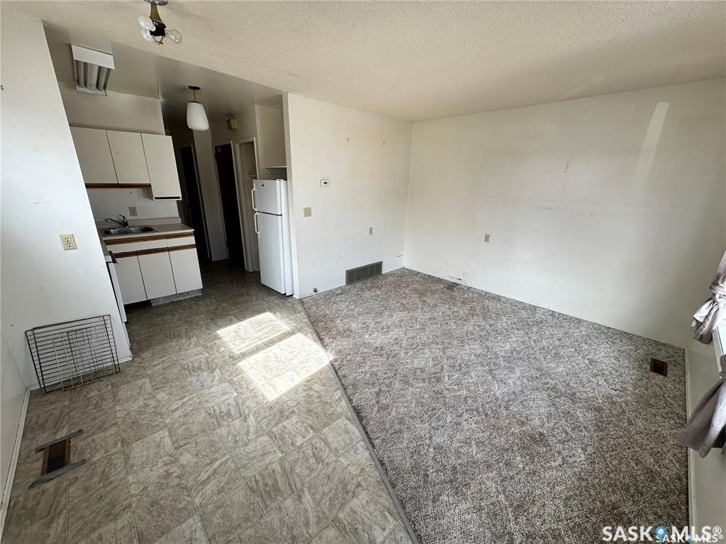 Kitchen area with white cabinetry and a double-door refrigerator
