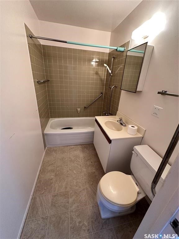 Bathroom featuring a white bathtub, ceramic wall tiling, a vanity with an integrated sink, a built-in medicine cabinet, and tiled flooring