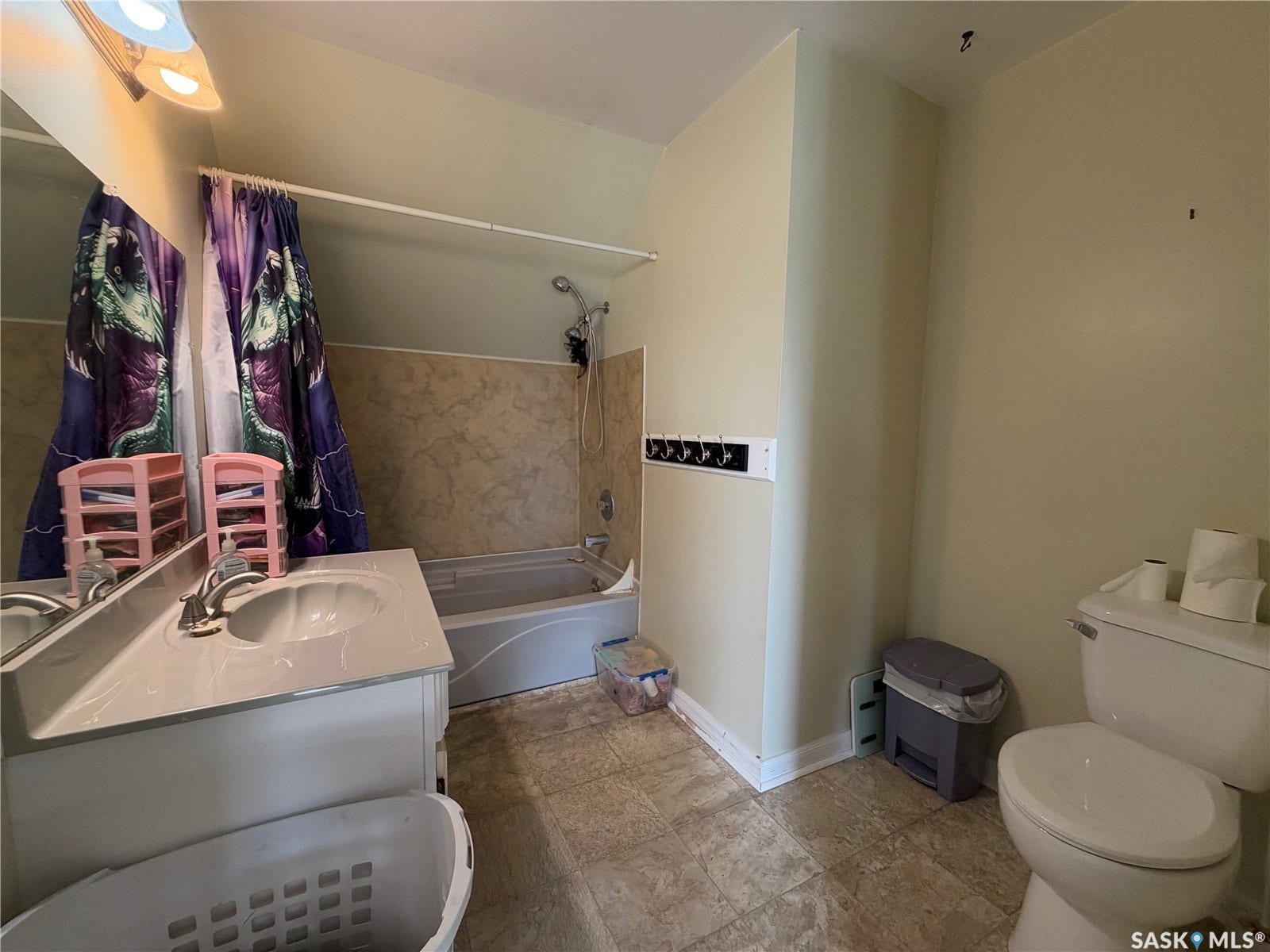 Bathroom featuring a white vanity with integrated sink, a built-in bathtub with wall-mounted shower head, and neutral wall tiling