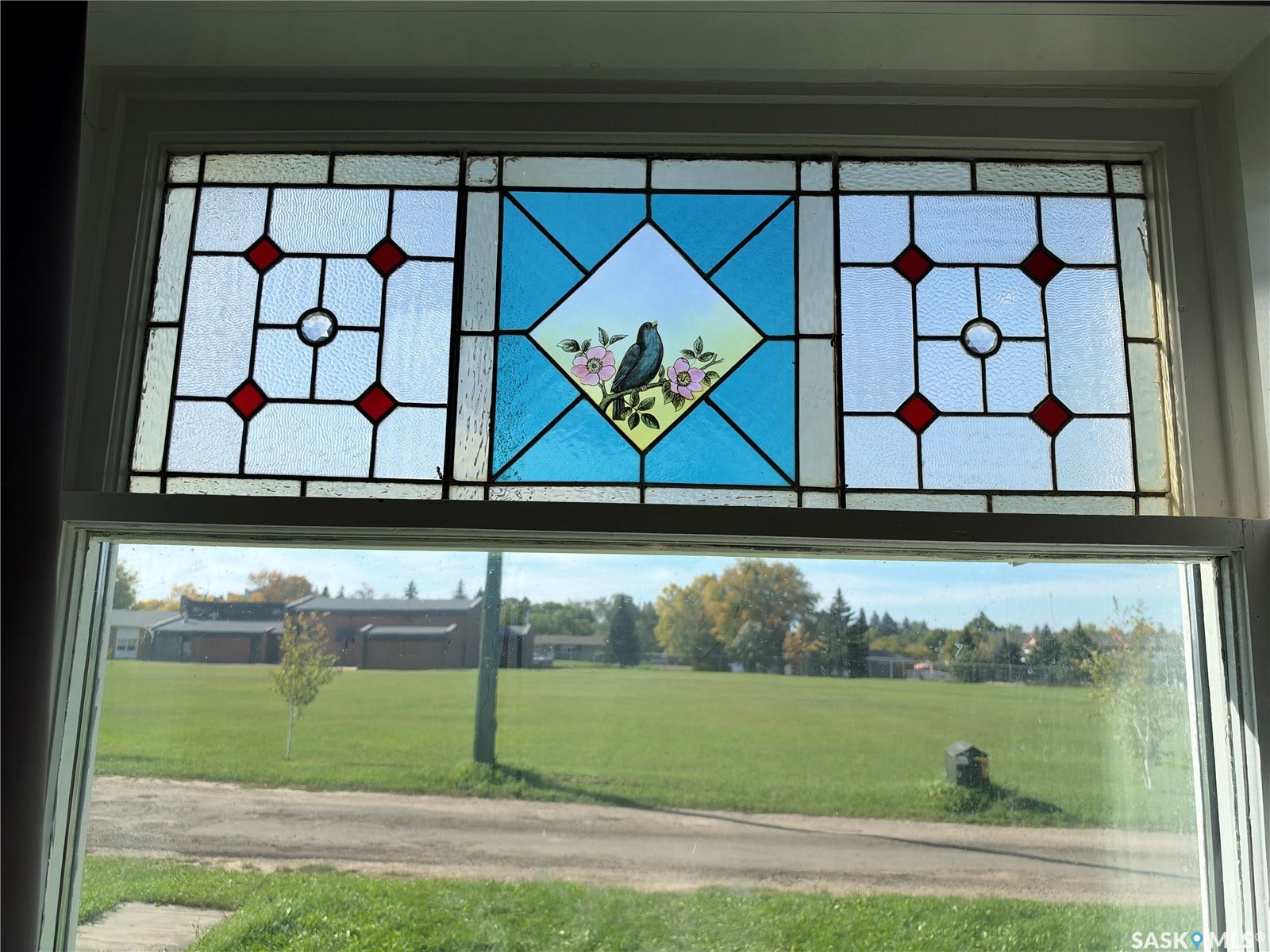 Stained glass transom window featuring a central bird and floral motif