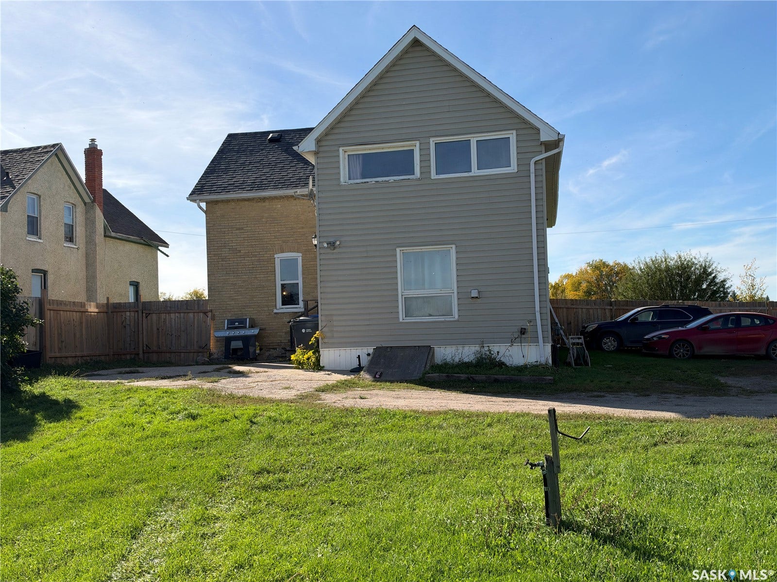Siding exterior with multiple windows, pitched roof, and a gravel driveway