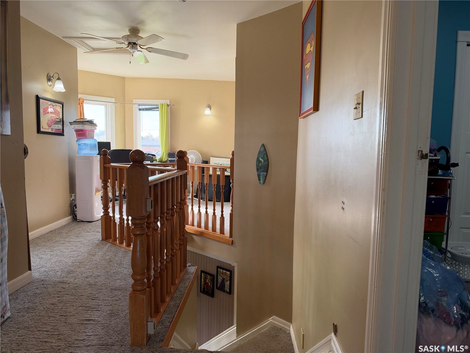 Carpeted hallway with wood banister and wall-mounted light fixtures