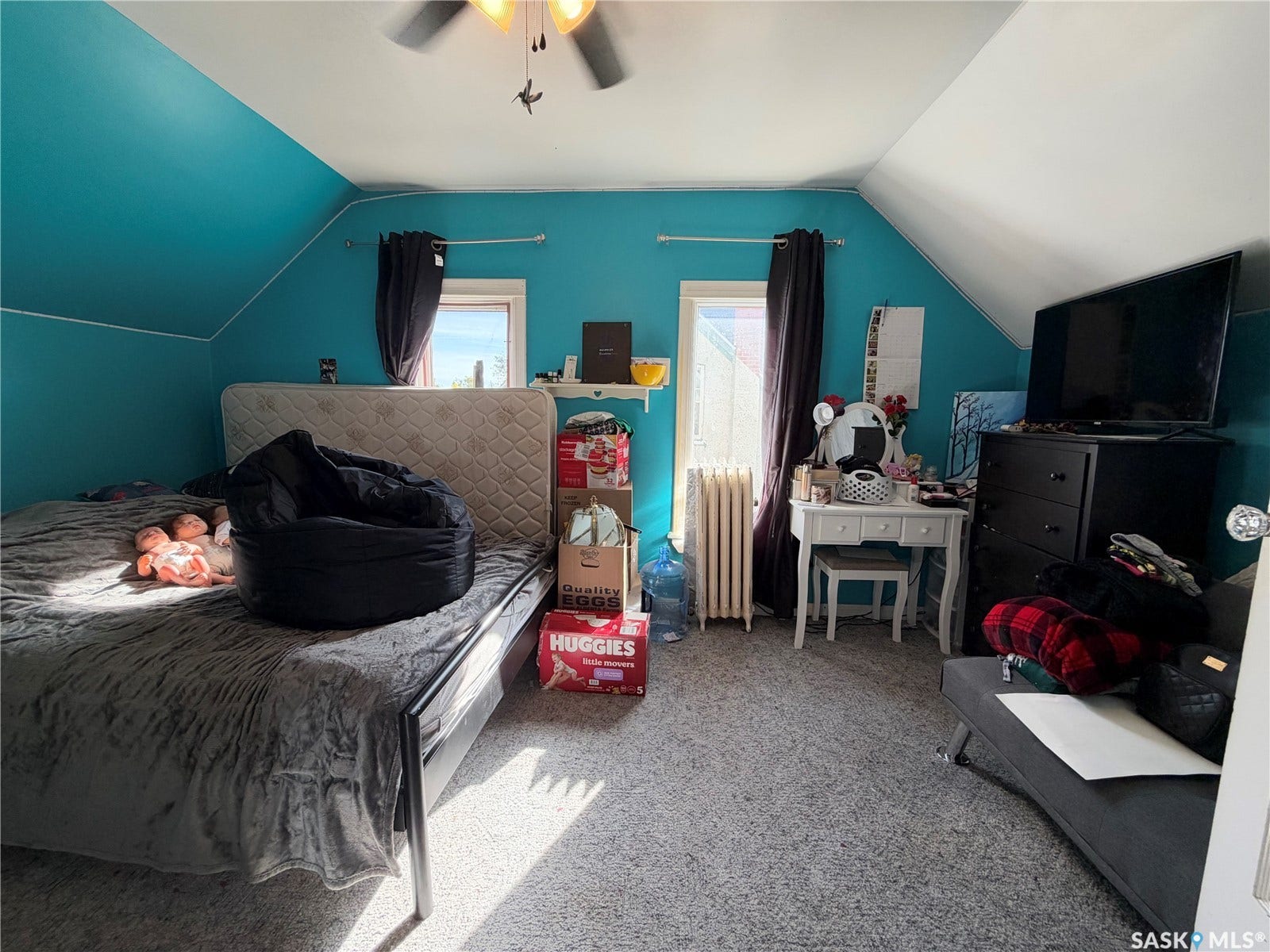 Angled ceiling, two windows, wall-mounted shelving, overhead ceiling fan