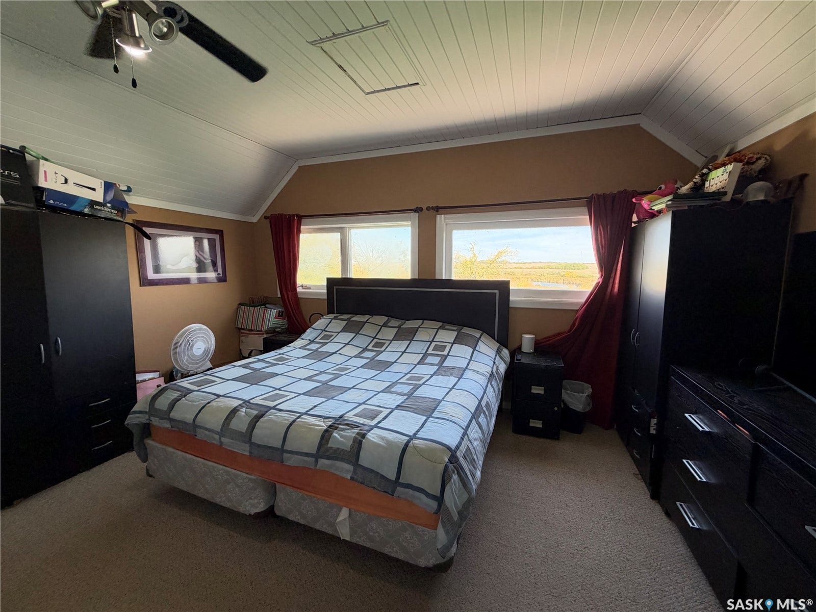 Vaulted ceiling with wood paneling, ceiling fan with integrated lighting, and two windows