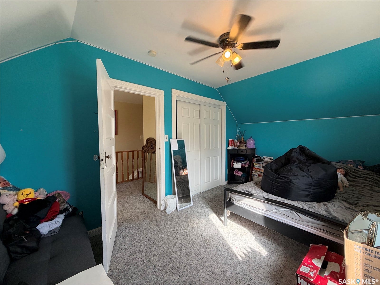 Sloped ceiling room featuring a ceiling fan with light, a built-in closet with bi-fold doors, and a carpeted floor