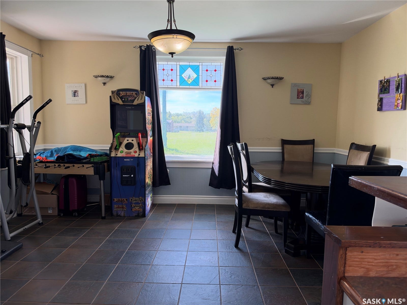 Tiled flooring, overhead light fixture, decorative wall sconces, and a large window with stained glass detailing