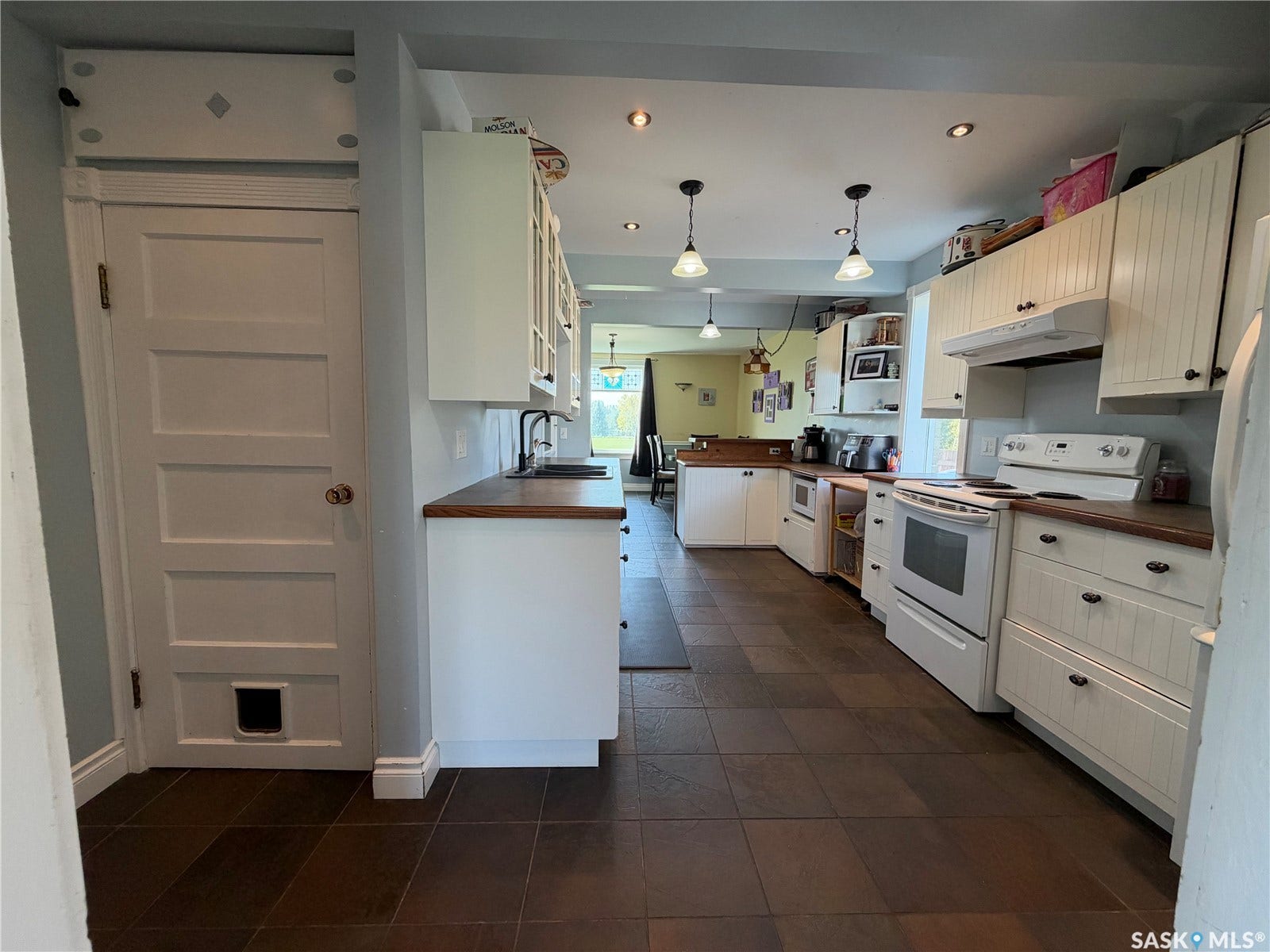 Spacious kitchen featuring white cabinetry, dark wood-finish countertops, and dark tile flooring