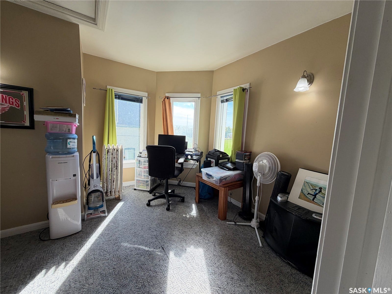 Room featuring three windows, wall-mounted lighting, and carpeted flooring