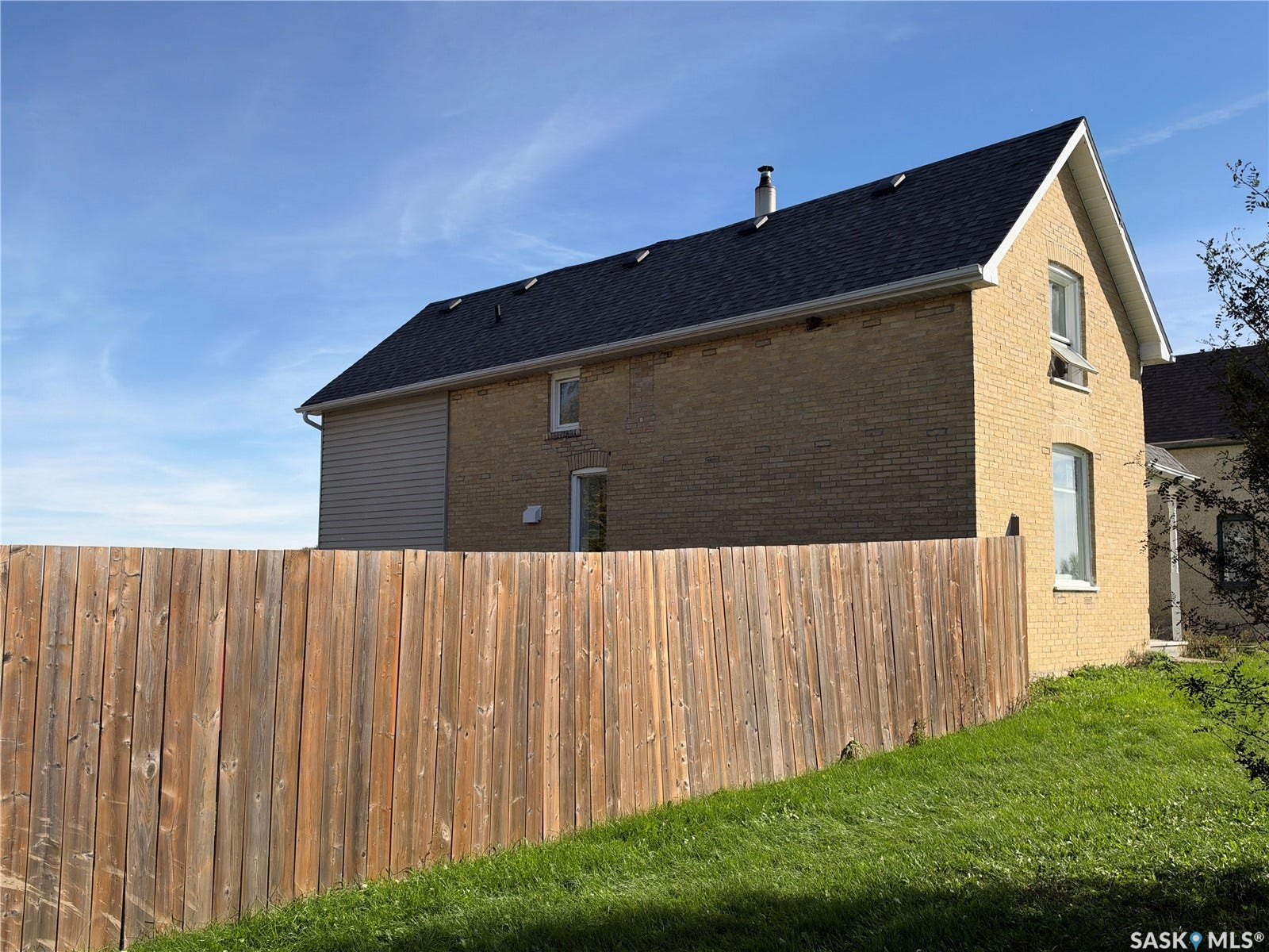 Brick exterior with white window trim, dark shingle roof, and light-colored siding
