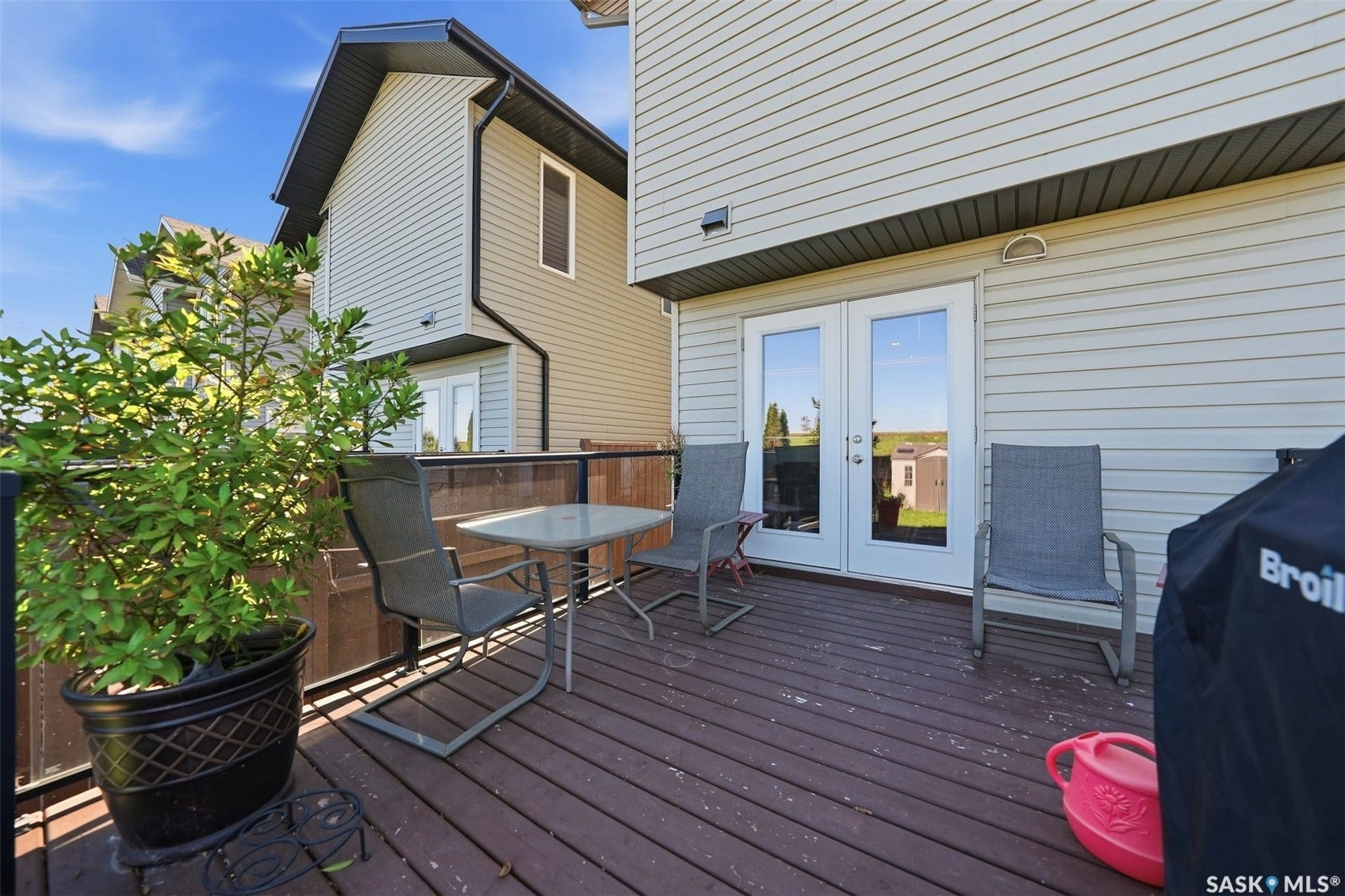 Wood-finish deck with glass panel railing and double French doors