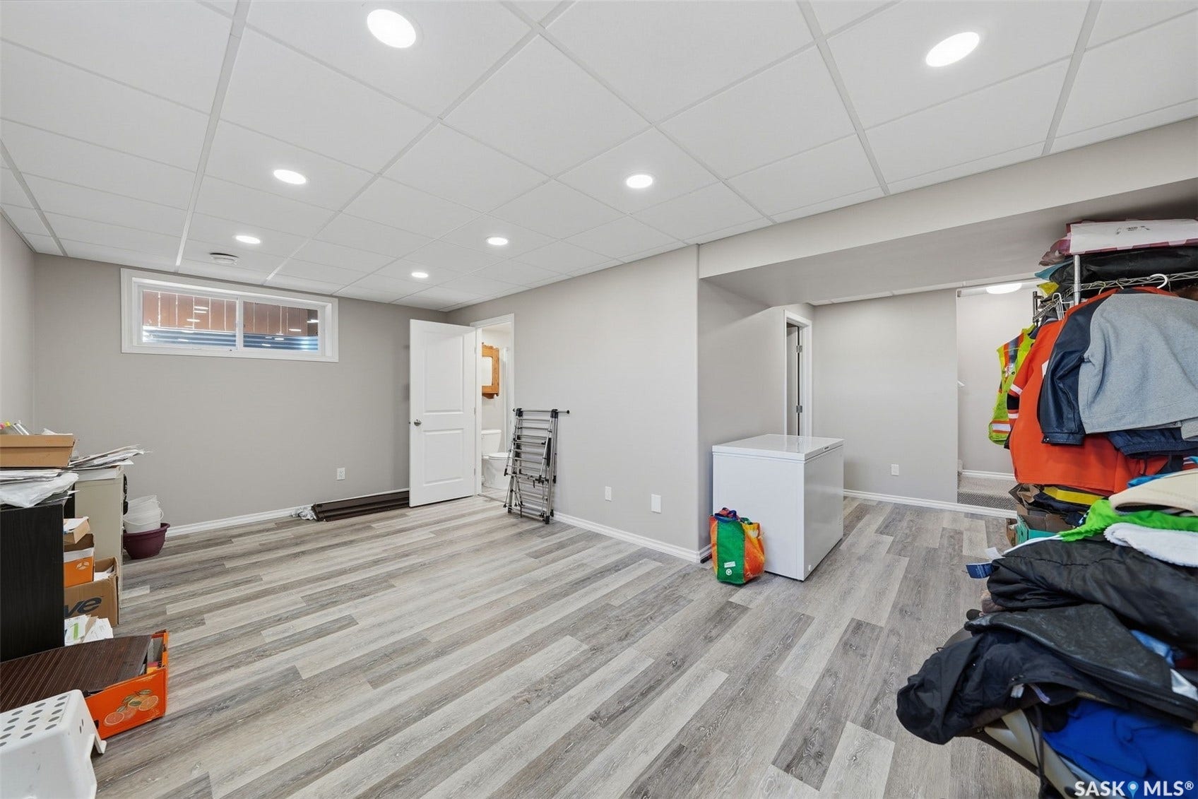 Recessed lighting, drop ceiling, wood-finish flooring, white trim, and a window for natural light