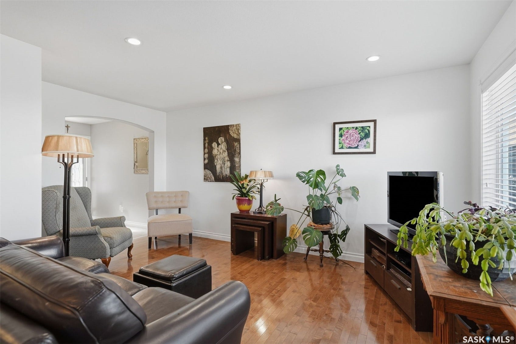 Wood-finish flooring throughout, recessed ceiling lighting, arched doorway, and window with horizontal blinds
