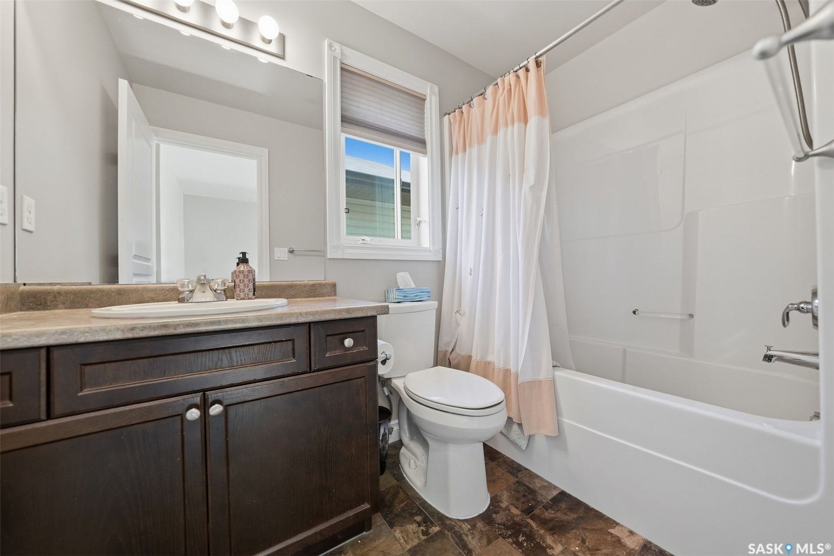 Dark wood-finish vanity with a single basin and chrome faucet, under-counter storage, and a light-toned countertop
