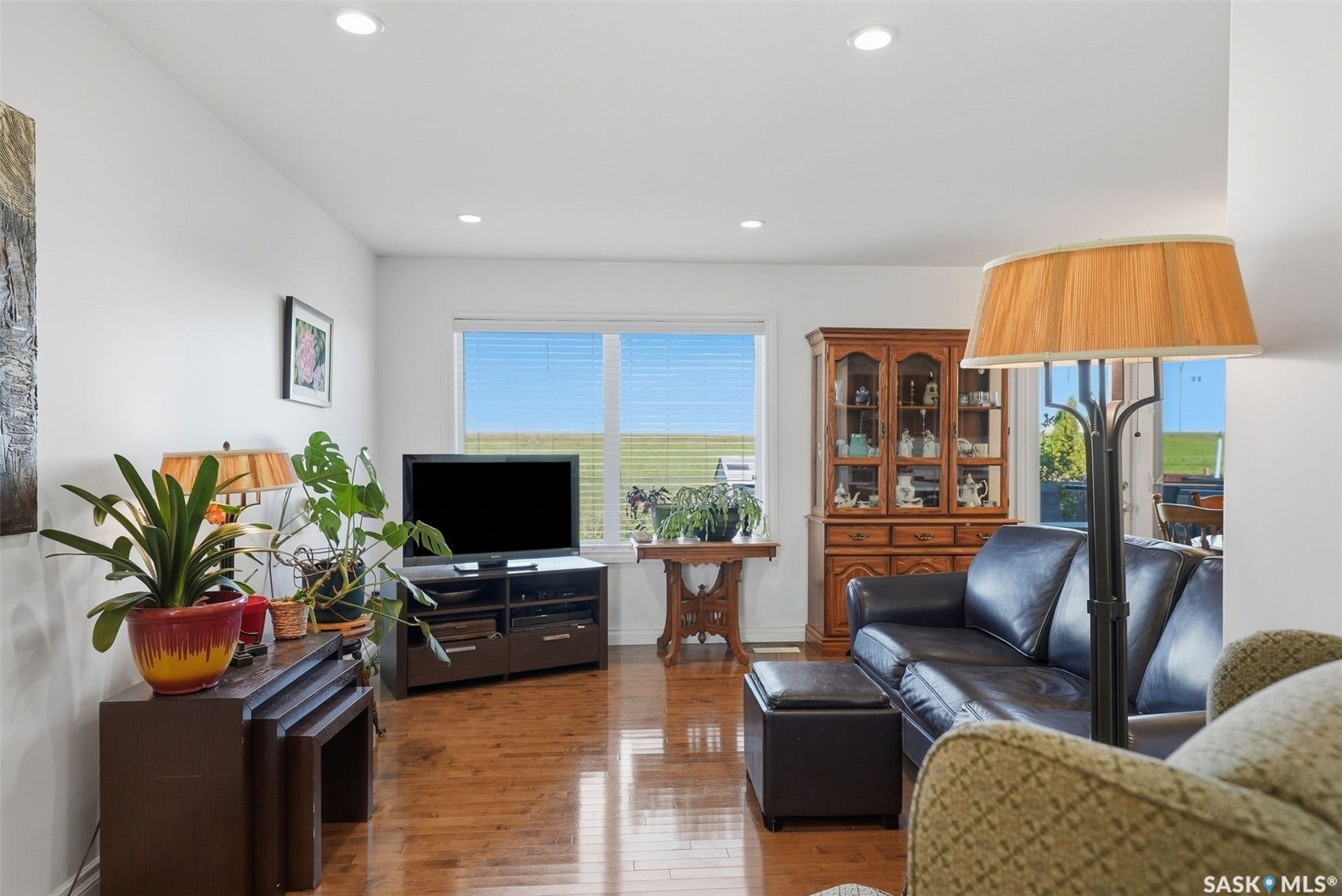 Recessed lighting, wood-finish flooring, white walls, and a large window