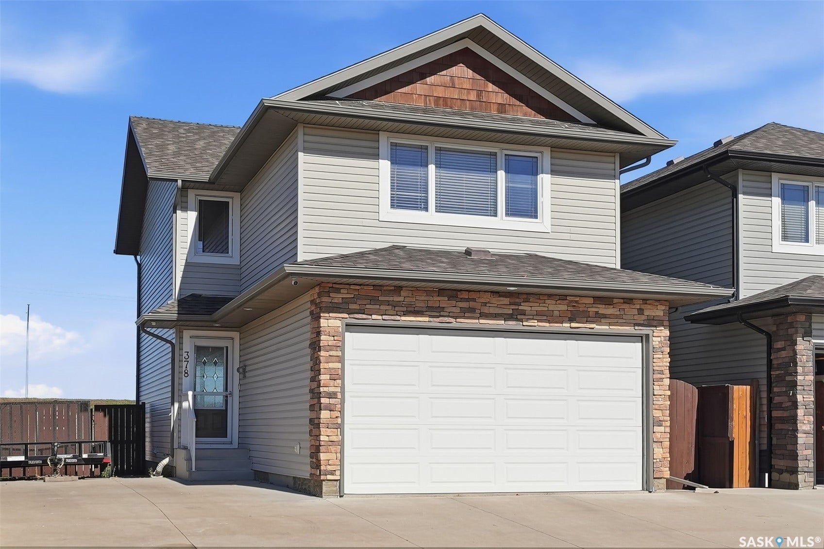 Two-story residence featuring light-toned siding and a prominent attached garage