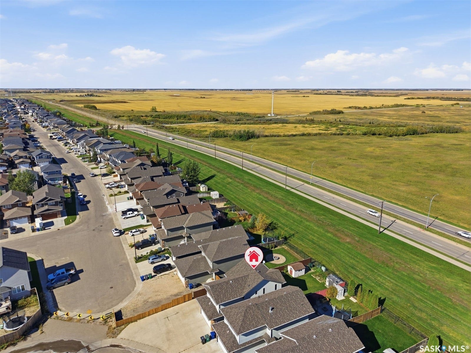 Single-story residence with a fenced backyard, adjacent to an open field and a paved roadway