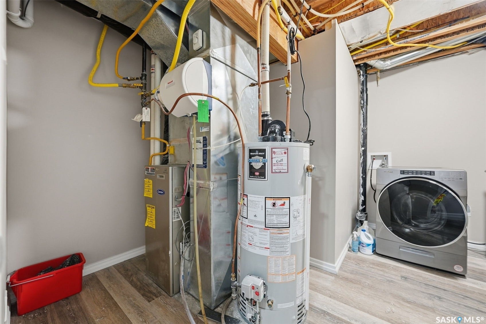 Laundry area featuring a front-load washing machine, water heater, and furnace