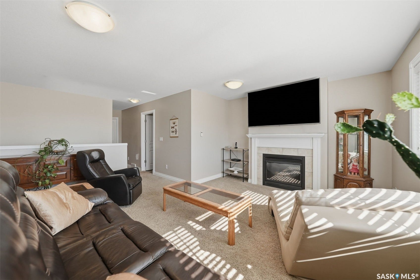 Carpeted room featuring an integrated fireplace with a light-toned mantle and hearth