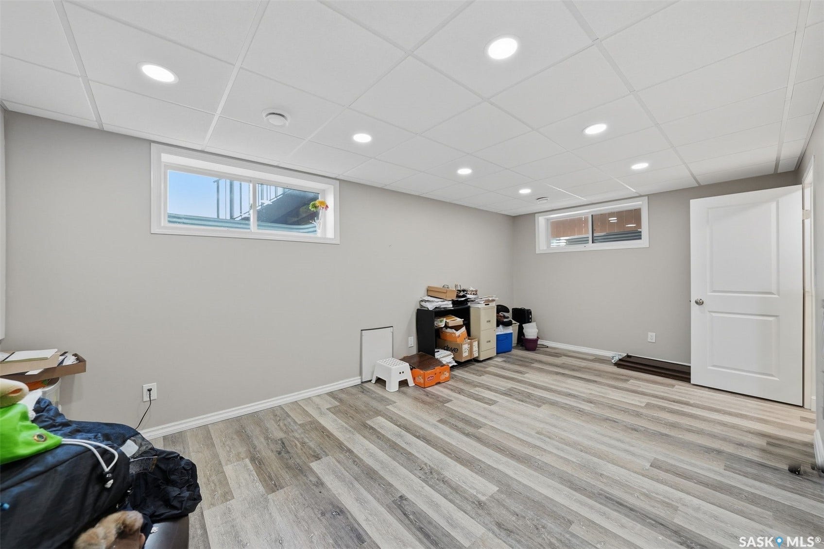 Recessed lighting, drop ceiling, wood-finish flooring, two windows, and a panel door