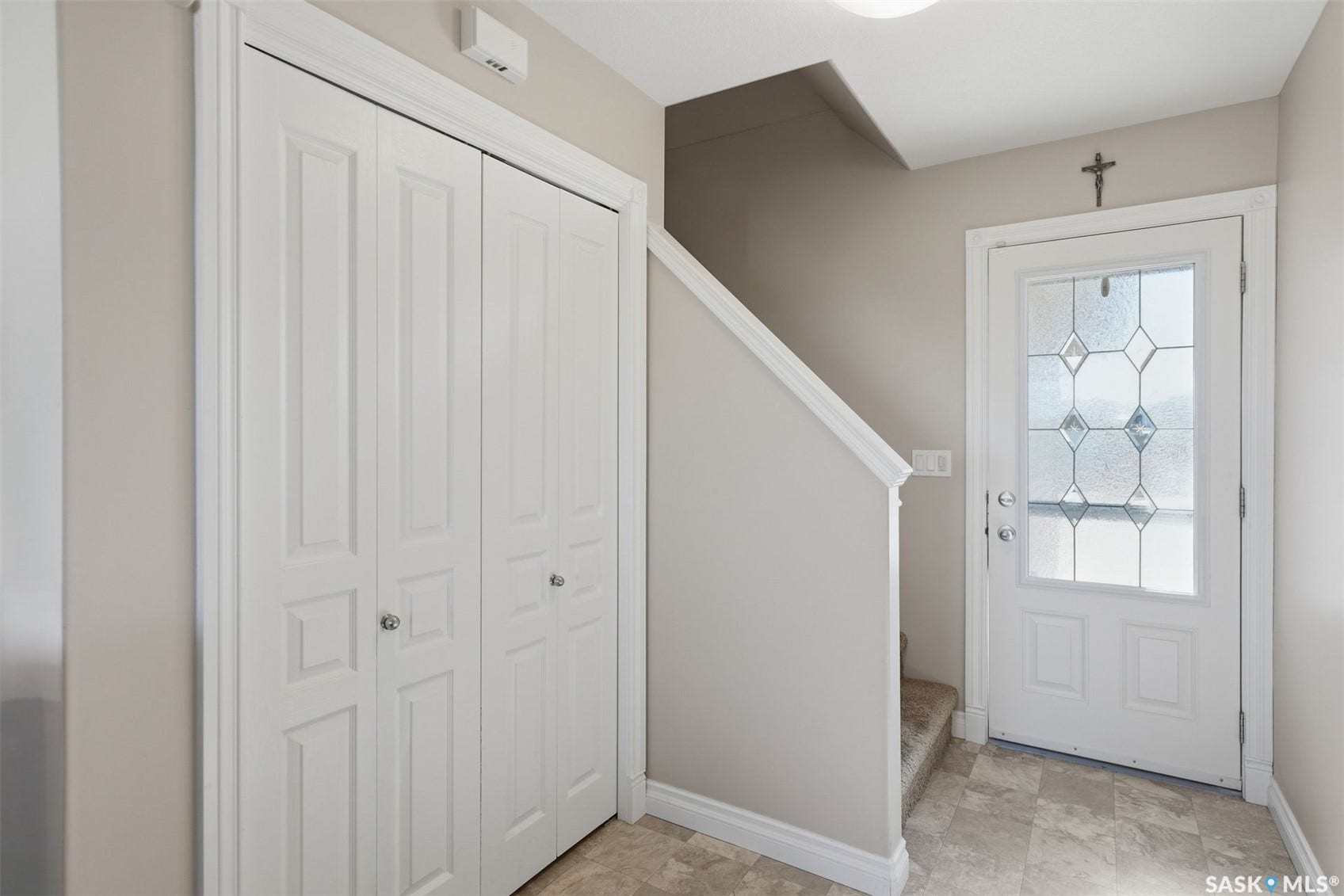 Entryway featuring a white paneled door with decorative glass, light-toned wall paint, and bi-fold closet doors