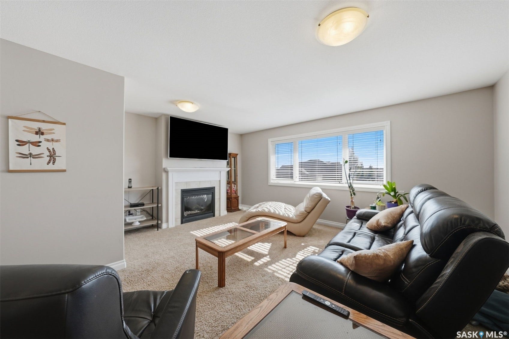 Carpeted living area featuring a built-in fireplace with a white mantel, multiple windows with blinds, and flush-mount lighting fixtures