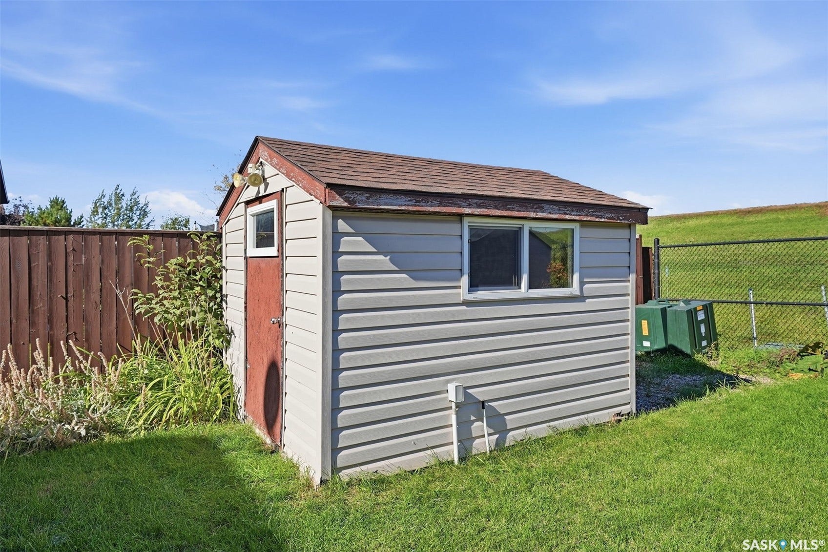 Storage shed with vinyl siding, shingle roof, and a single window