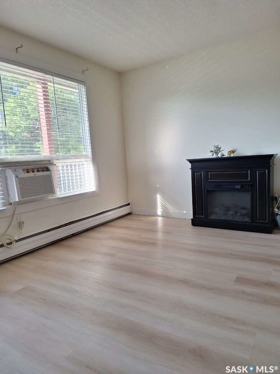 Light wood-finish flooring, white painted walls, and a built-in fireplace feature