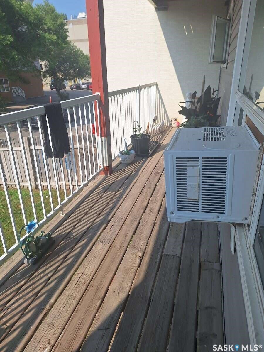 Balcony with wood-finish flooring, white metal railing, and a window-mounted air conditioning unit