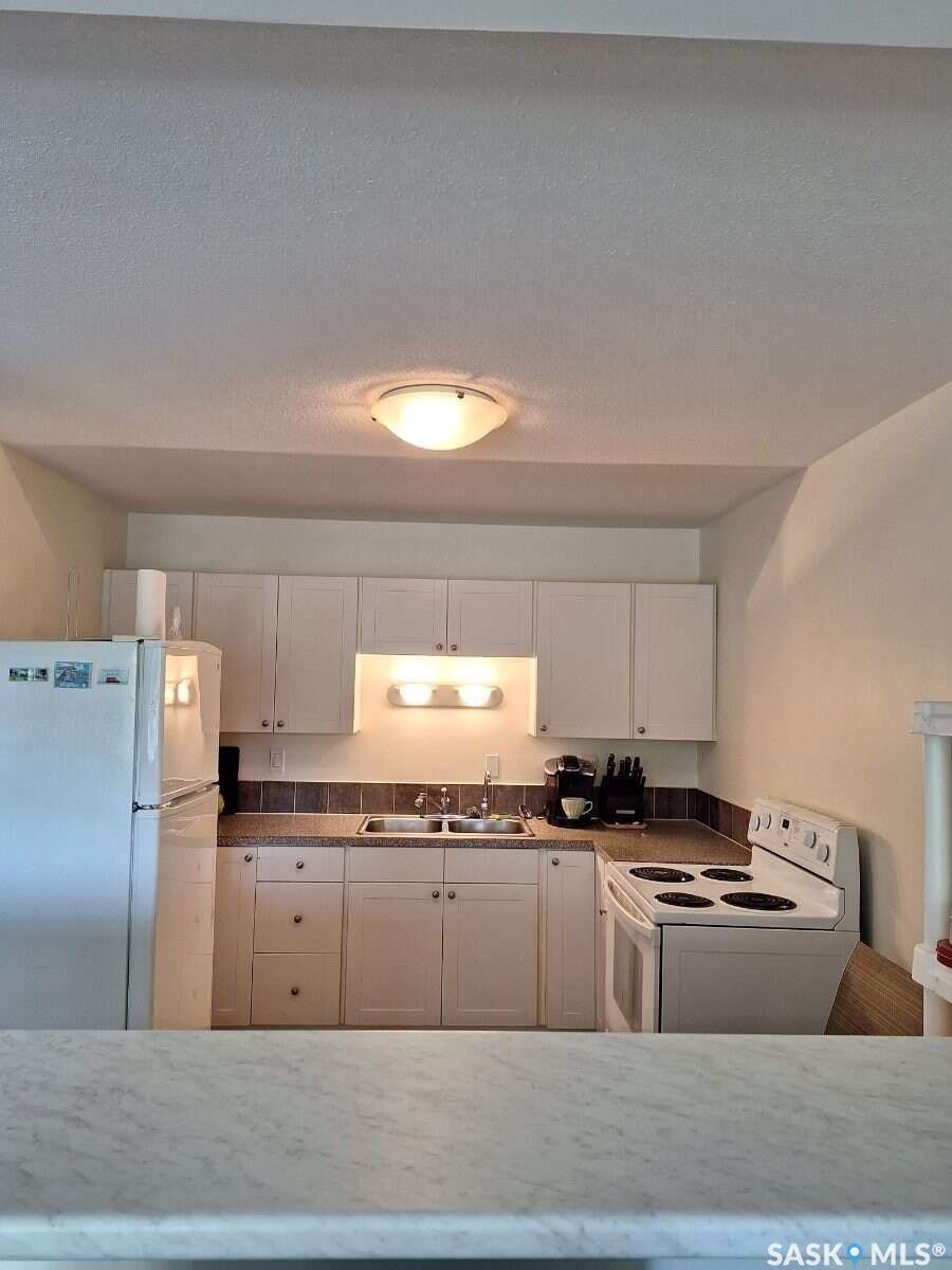 Kitchen featuring white cabinetry, a double basin sink, and a four-burner electric range