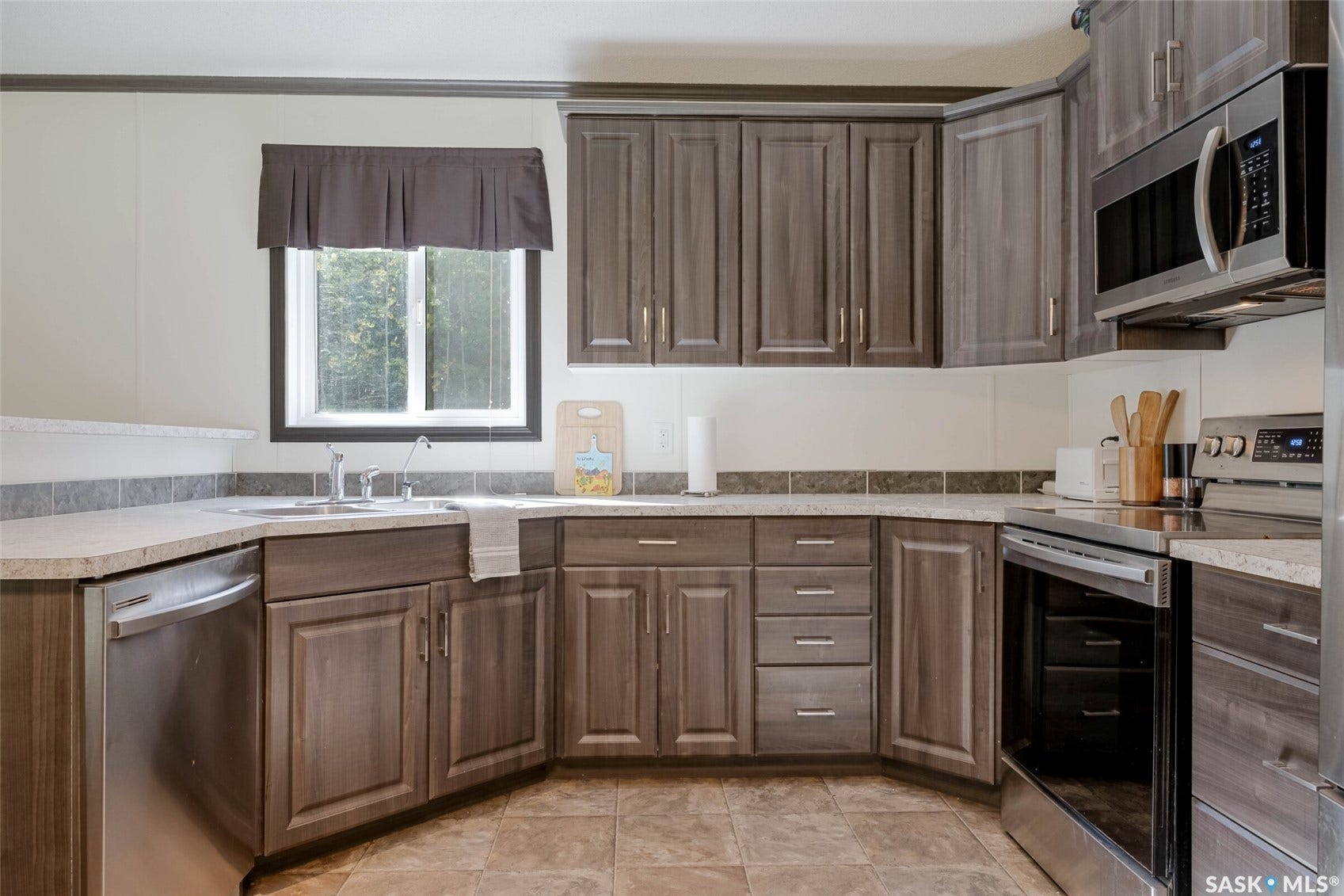 Corner kitchen with wood-finish cabinetry, stainless steel appliances, and a double basin sink