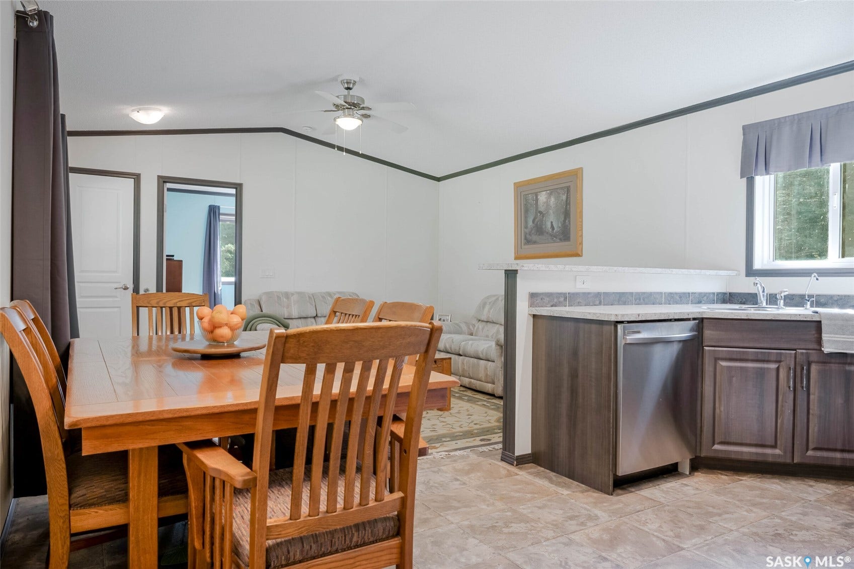 Kitchen featuring wood-finish cabinetry, stainless steel dishwasher, and a window above the sink