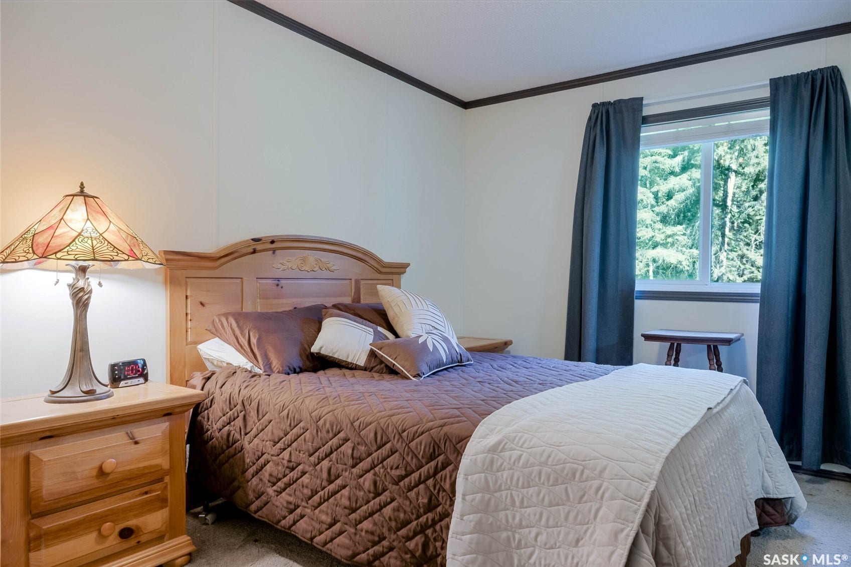 Wood-finish bed frame, nightstand with built-in drawers, and window with outdoor scenery