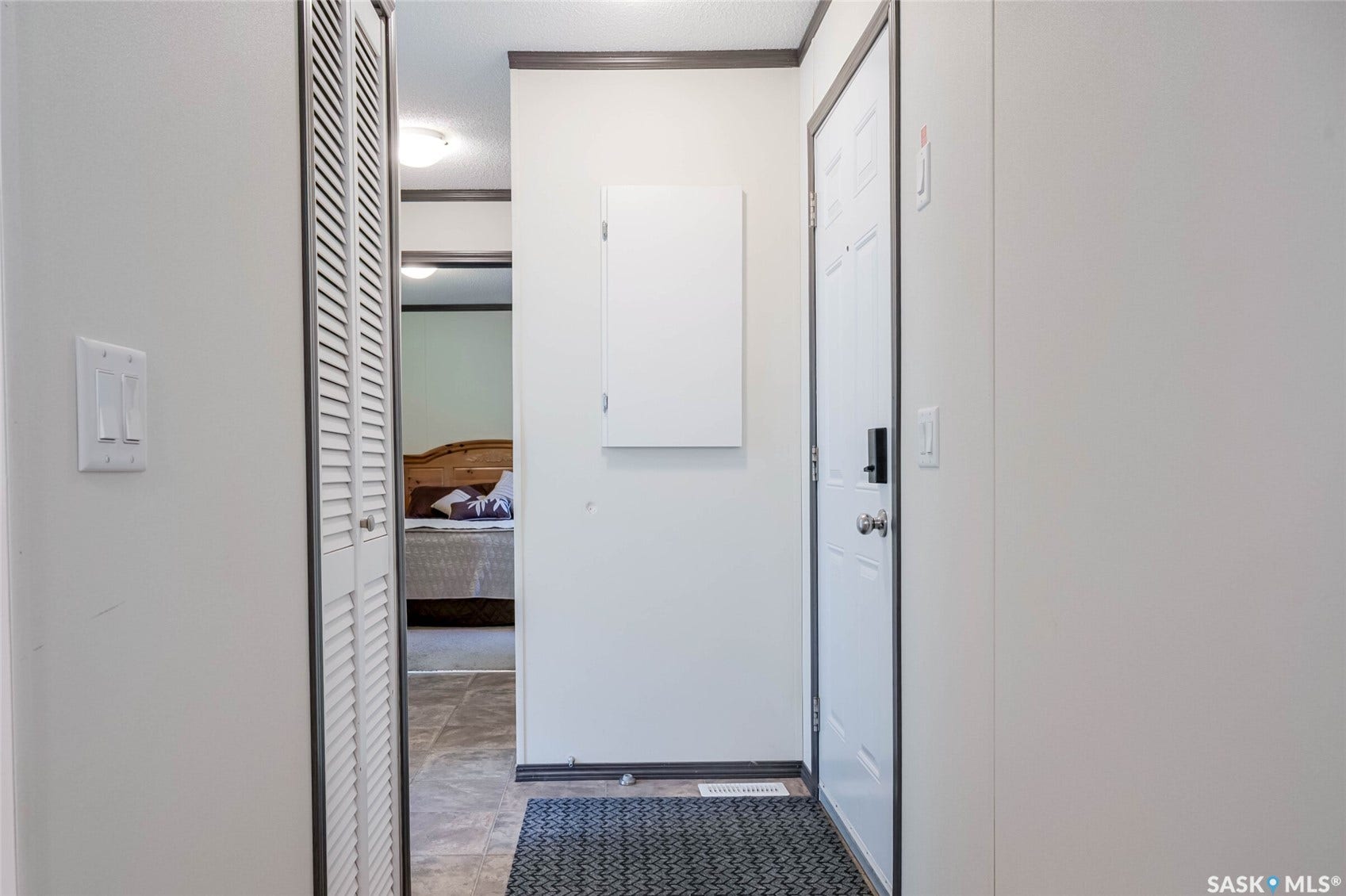 Entryway featuring a white paneled door, louvered bi-fold closet doors, and wall-mounted light switches