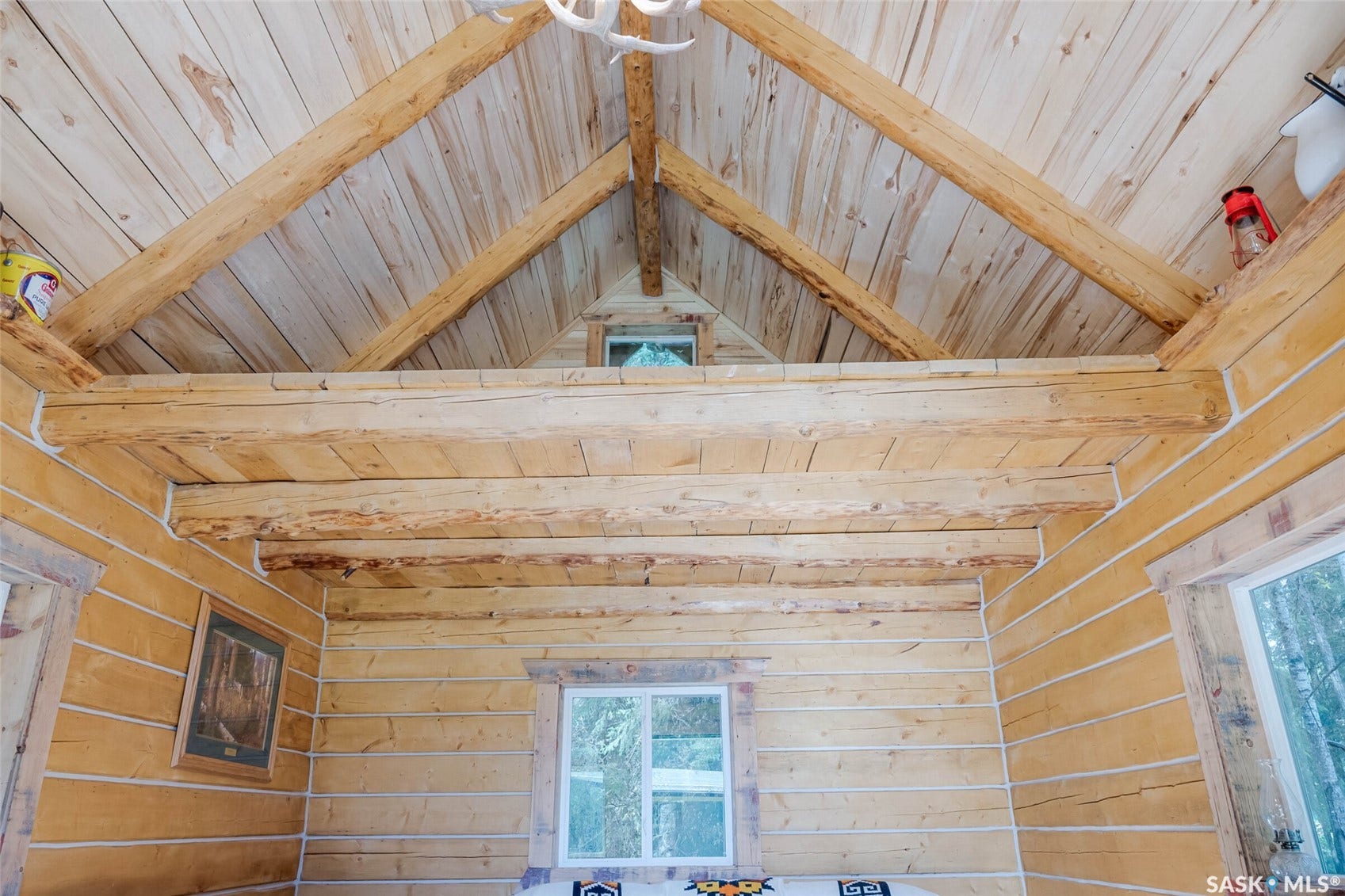 Exposed wood beam construction, natural wood plank walls, tongue and groove ceiling, and multiple windows providing natural light