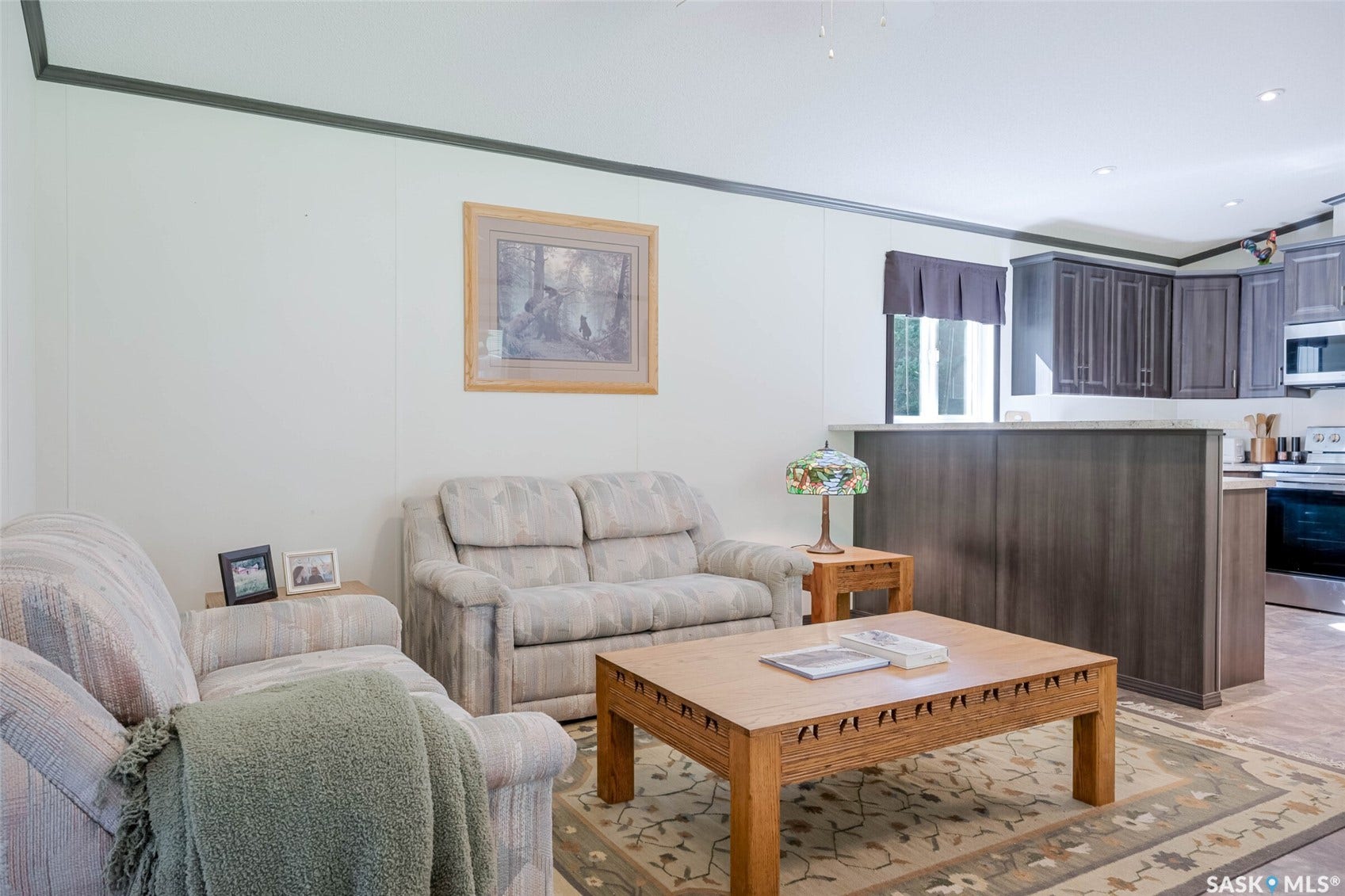 Open-concept living space with dark wood-finish cabinetry, stainless steel appliances, and a breakfast bar