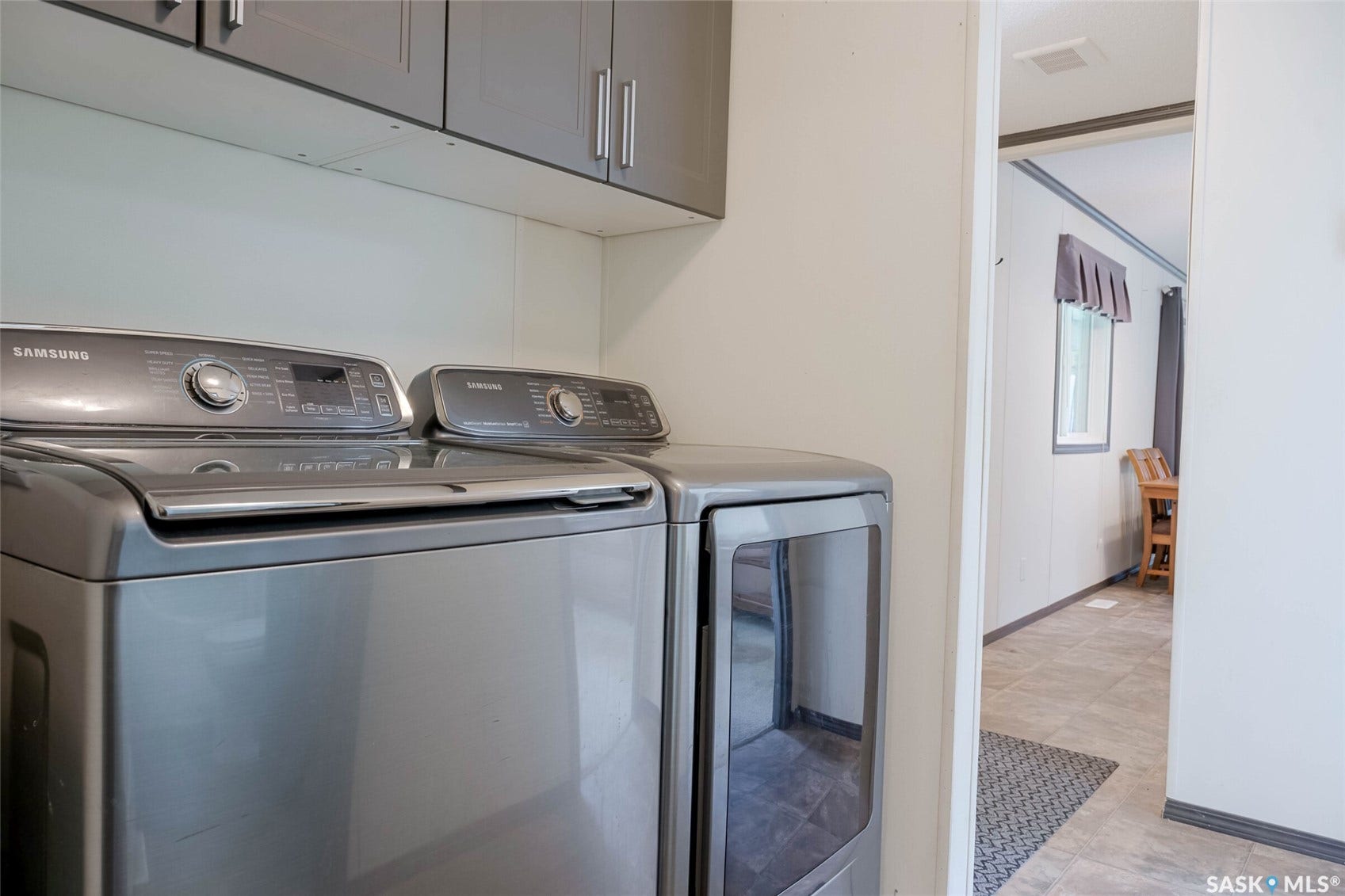 Integrated laundry area featuring upper cabinetry with brushed nickel hardware