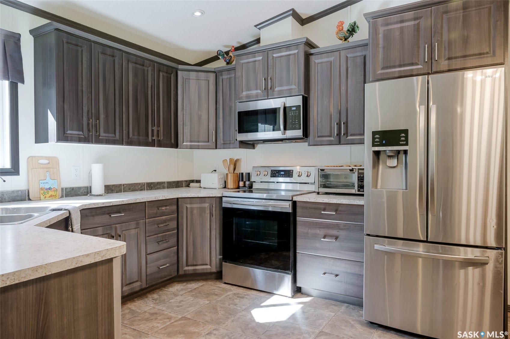 Contemporary kitchen featuring wood-finish cabinetry, stainless steel appliances, and L-shaped countertops