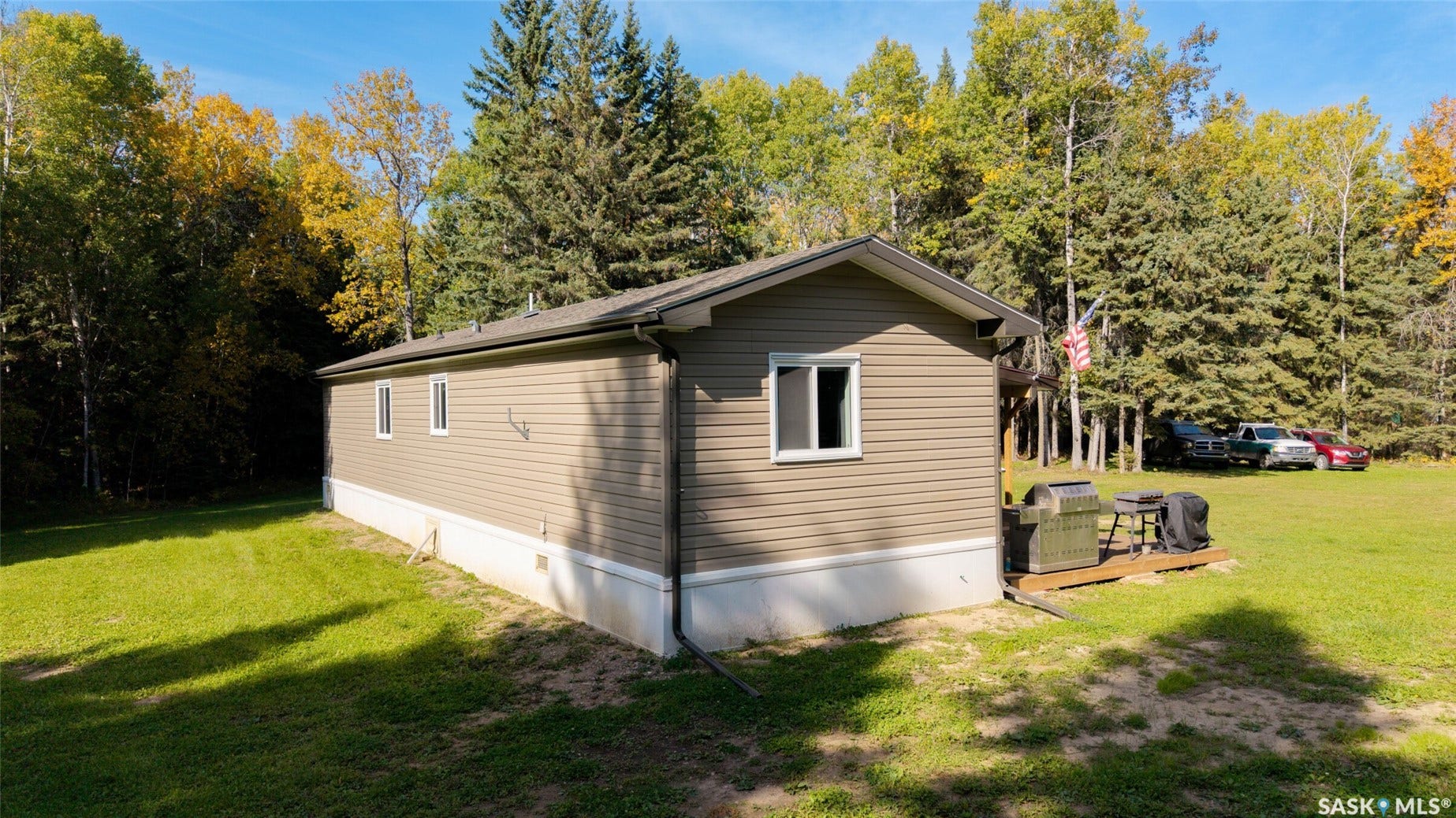Wooded lot with a natural tree line, featuring a residence with horizontal siding and multiple white-framed windows