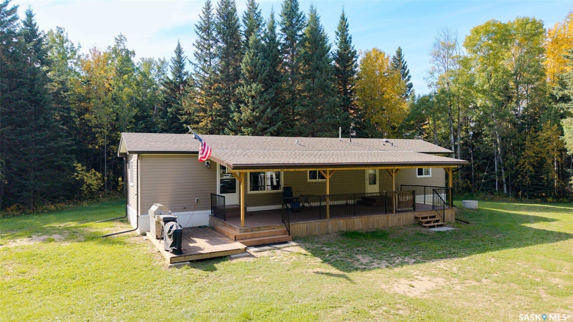 Expansive rear deck featuring a covered area, wood-finish decking, and black metal railings